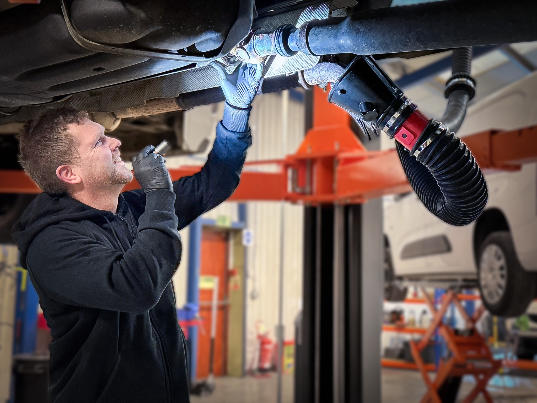 A Dash Fleet Services technician inspecting the underside of a lifted vehicle